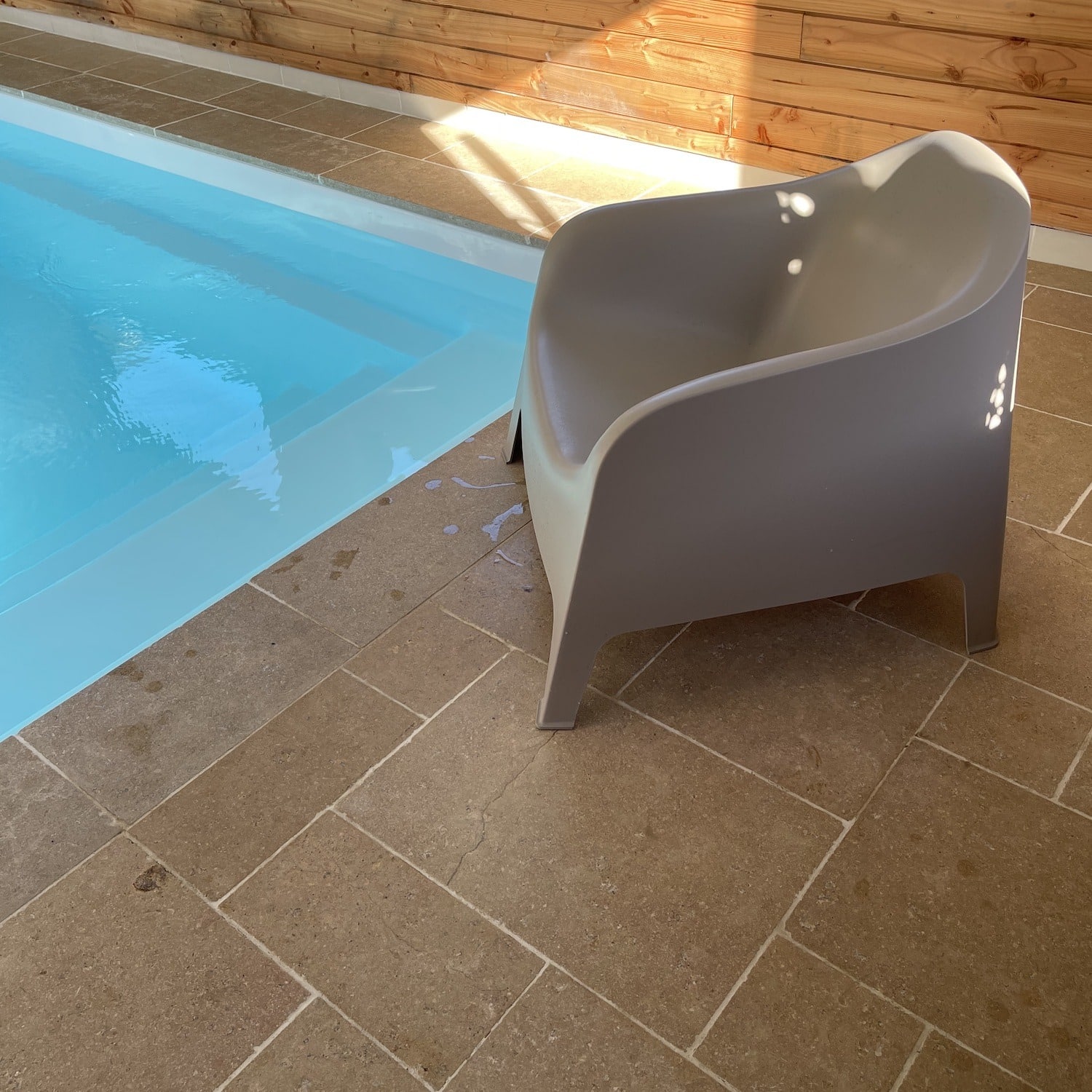 fauteuil-autour-de-la-piscine-entourée-d'une-dalle-beige-exterieur-egypta-posé-en-opus-romain-et-margelles-de-piscine