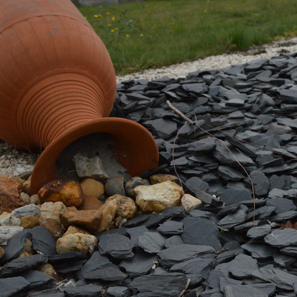 Amphore dans un massif en paillage en ardoises noires.